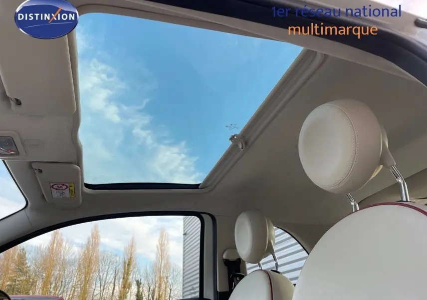 Intérieur clair de la Fiat 500 blanche 2022, vue sur toit ouvrant panoramique et sièges avant en cuir blanc.