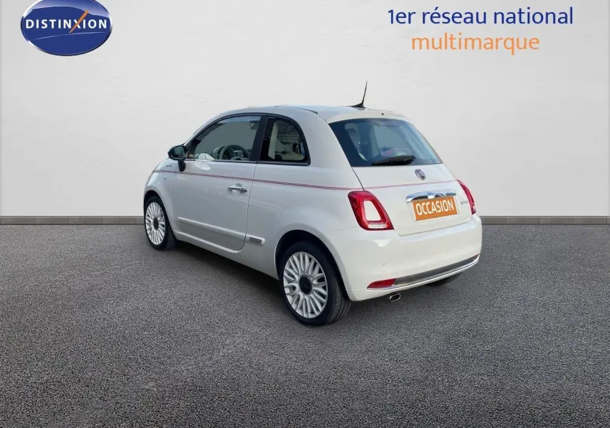 Vue 3/4 arrière gauche d'une Fiat 500 blanche 1.0 Hybrid 70CH DolceVita avec jantes biton et bande rouge décorative sur la carrosserie.