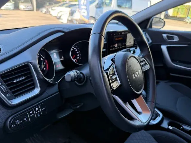 Intérieur de la KIA CEE'D 2024 vu côté conducteur, volant cuir noir avec logo KIA et tableau de bord digital.