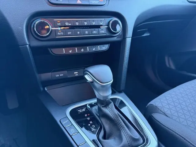 Gros plan sur la console centrale de la Kia CEE'D 2024 argent lunaire, mettant en valeur le levier de vitesse automatique et les commandes climatiques.
