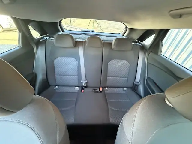 Vue arrière intérieure des sièges arrière gris foncé de la KIA CEE'D 2024, avec ceintures de sécurité visibles.