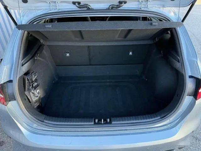 Coffre ouvert vu de l'arrière d'une KIA CEE'D argent lunaire 2024, montrant un espace de rangement propre et spacieux.