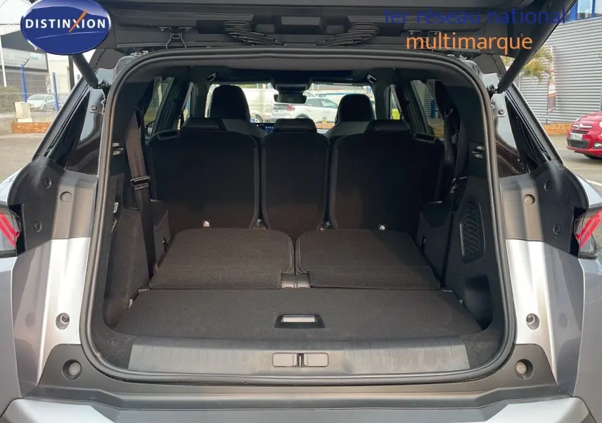 Coffre ouvert d'un Peugeot 5008 gris Artense avec toit noir, montrant les sièges arrière rabattus et l'espace de chargement.