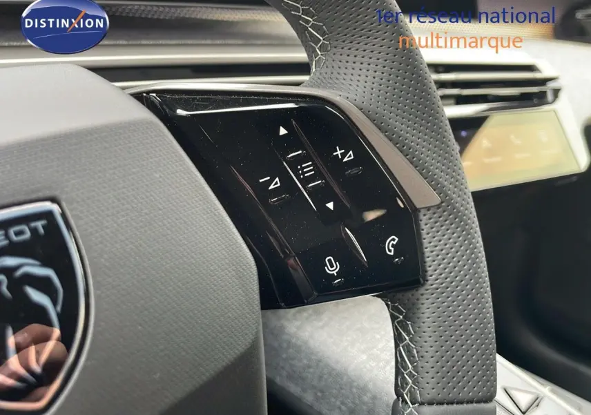Gros plan sur le volant en cuir perforé gris du Peugeot 5008 Hybrid 136ch GT, avec commandes tactiles intégrées.