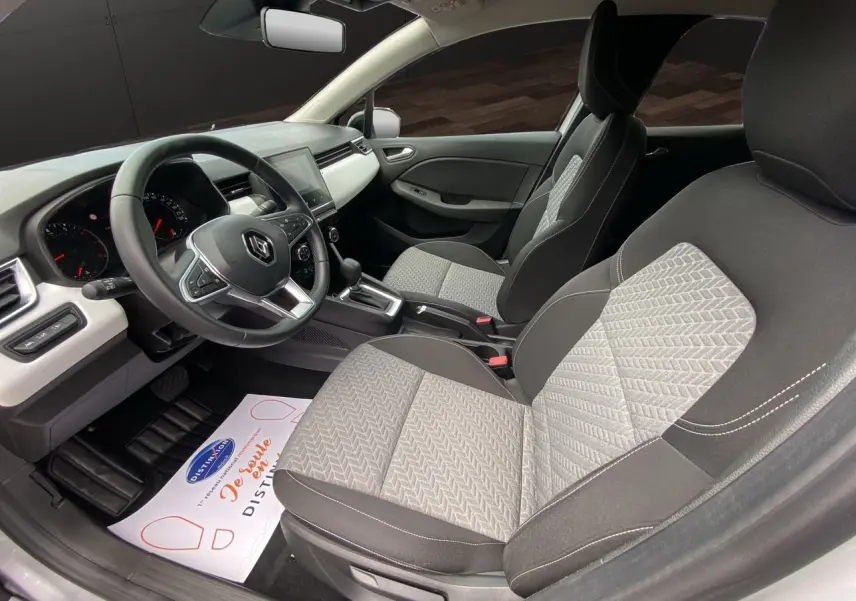 Intérieur avant de la Renault Clio V TCE 90 gris Highland, sièges tissu bicolore et tableau de bord moderne.