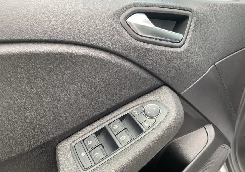 Gros plan sur la commande des vitres électriques côté gauche de la porte intérieure noire d'une Renault Clio V gris Highland.