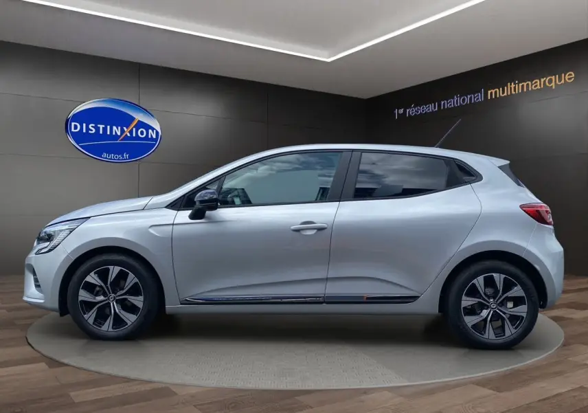 Profil droit d'une Renault Clio V gris Highland avec jantes alliage et vitres teintées en showroom.