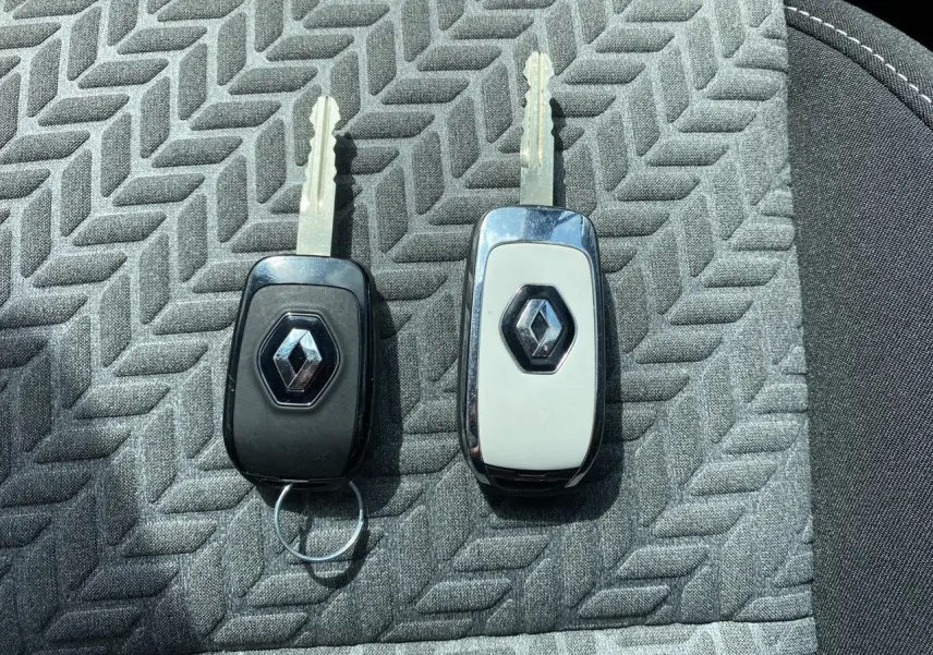 Gros plan sur deux clés Renault posées sur un siège en tissu gris à motif géométrique.
