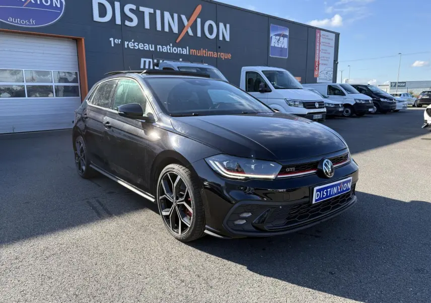 Volkswagen Polo GTI noire en 3/4 avant droit, avec jantes alliage 18 pouces et calandre GTI rouge.