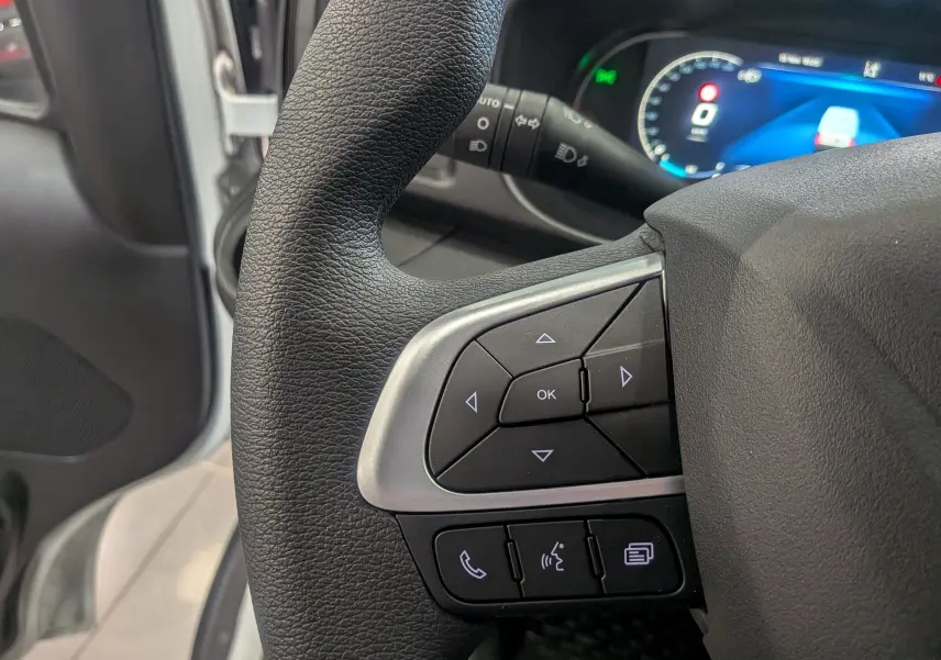 Gros plan sur les commandes au volant noir et argent du tableau de bord du fourgon Iveco Daily 2025 blanc.