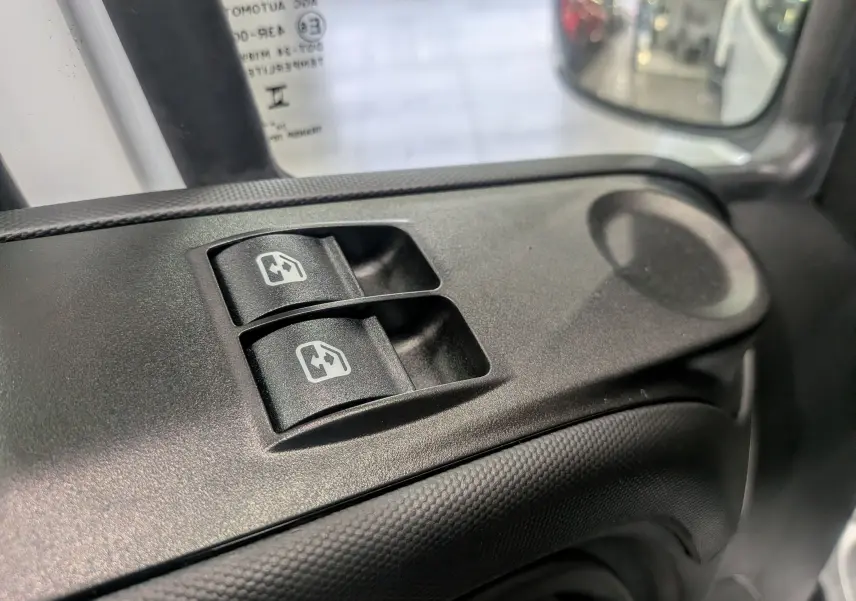 Boutons de commande des vitres électriques sur la portière côté gauche d'un Iveco Daily Fourgon blanc 2025.