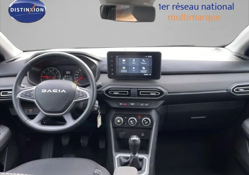 Vue intérieure frontale du tableau de bord noir du Dacia Jogger 2025 avec volant, écran tactile et boîte manuelle.