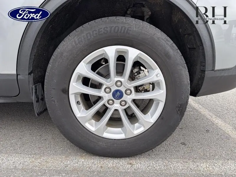 Gros plan sur la roue avant gauche du Ford Kuga gris Solar Métallisé avec jante alliage et logo Ford central.