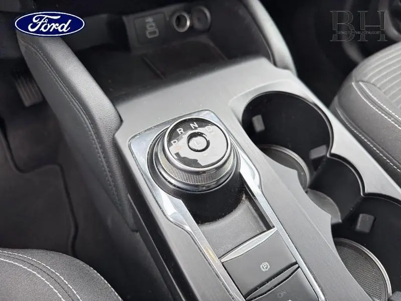 Vue rapprochée de la console centrale du Ford Kuga 2023, avec molette de boîte automatique et porte-gobelets noirs.