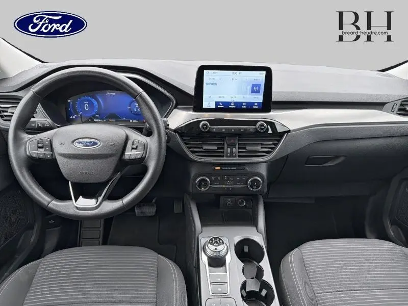 Vue intérieure avant du Ford Kuga 2023, tableau de bord moderne avec écran tactile central et volant multifonction noir.