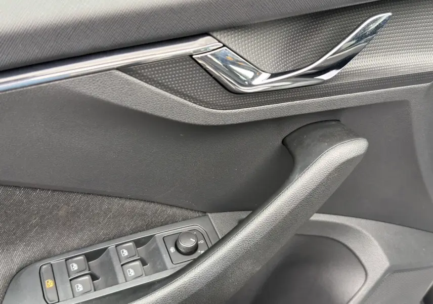 Vue intérieure côté conducteur du Skoda Kamiq 2023 gris foncé, avec sièges tissu bicolore et tableau de bord clair.
