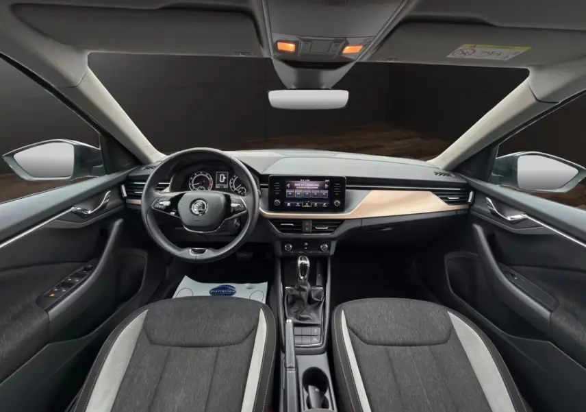 Vue intérieure côté gauche du Skoda Kamiq 2023 gris foncé, sièges tissu bicolore et tableau de bord bois clair.
