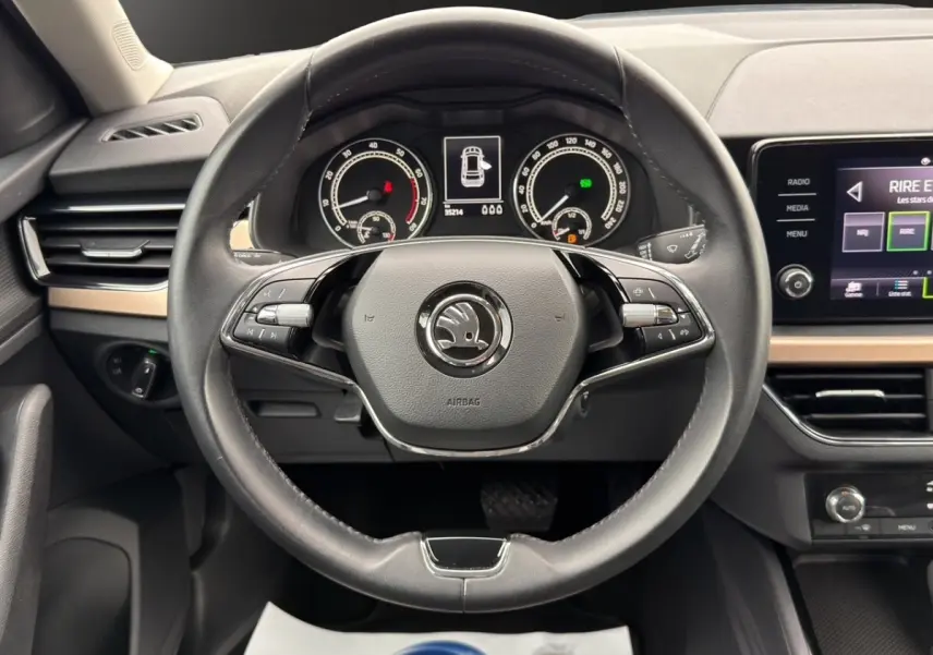 Vue intérieure avant du Skoda Kamiq 2023, tableau de bord clair avec écran tactile et sièges bi-ton gris foncé et clair.