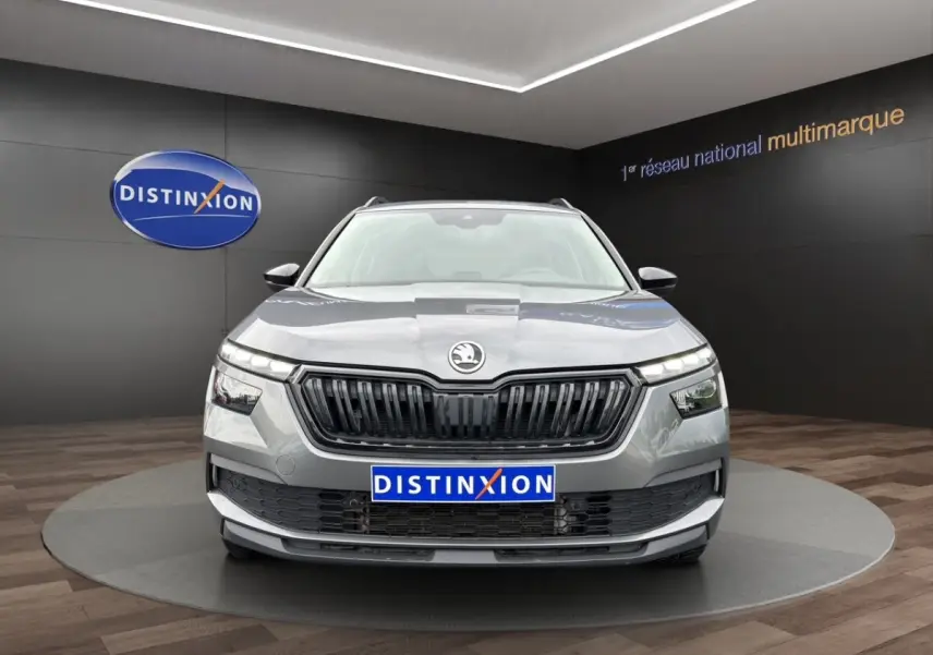 Vue 3/4 avant droite d'un Skoda Kamiq gris foncé avec jantes bi-ton et calandre noire en showroom.