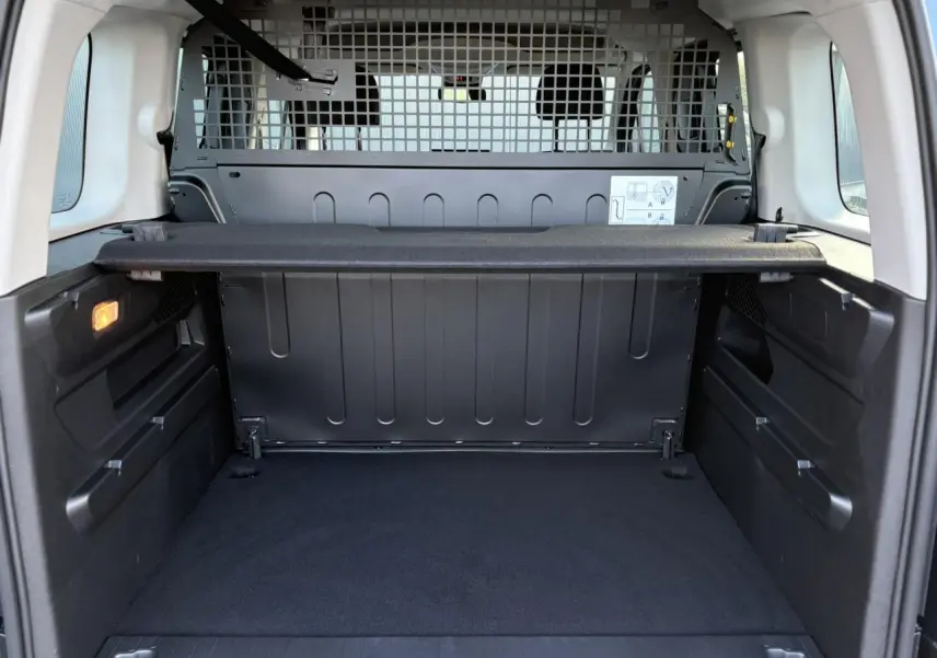 Vue intérieure du coffre du Citroën Berlingo Multispace bleu 2025, avec séparation grillagée et tablette de rangement.