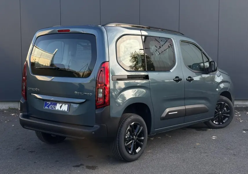 Vue 3/4 arrière droite d'un Citroën Berlingo Multispace bleu métallisé avec jantes alliage noires et barres de toit.