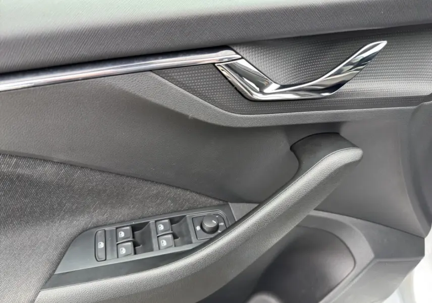 Vue intérieure côté conducteur du Skoda Kamiq 2023 gris clair, mettant en valeur les sièges tissu bicolores et le tableau de bord moderne.