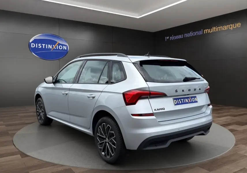 Vue de profil côté gauche d'un Skoda Kamiq gris clair 2023 avec jantes bi-ton et rétroviseurs noirs.