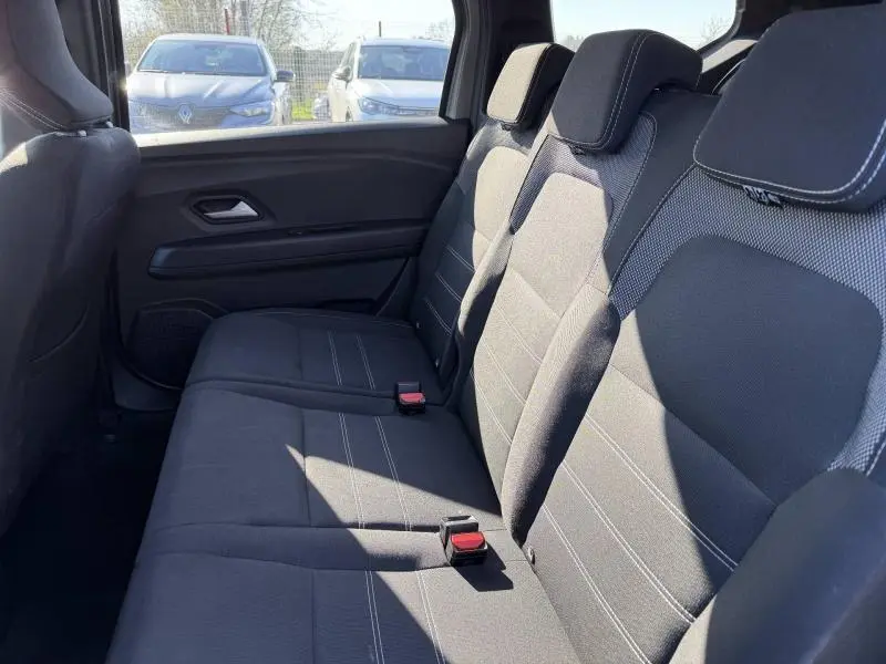 Vue latérale intérieure sur la banquette arrière en tissu gris du Dacia Jogger 2025, version 7 places, avec appuie-têtes.