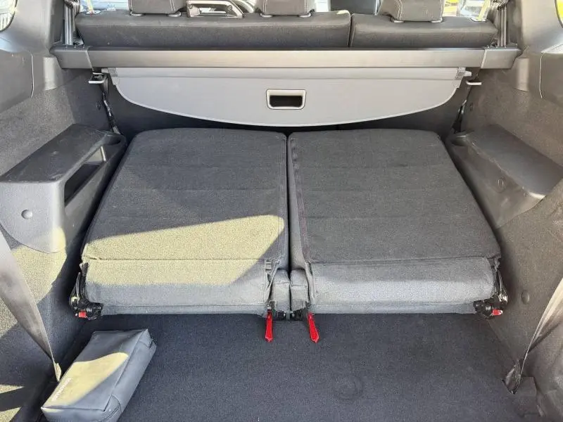 Vue du coffre du Dacia Jogger 2025 gris Schiste métallisé avec sièges arrière rabattus et cache-bagages déployé.