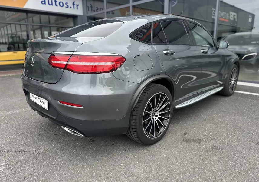 Vue 3/4 arrière droite d'un Mercedes GLC Coupé 250 D Fascination gris foncé avec jantes alliage et vitres teintées.