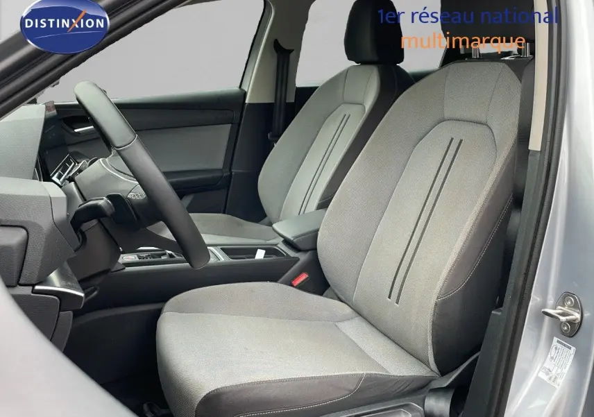 Intérieur côté conducteur du SEAT LEON ST gris urbain 2023, montrant sièges tissu gris et tableau de bord moderne.