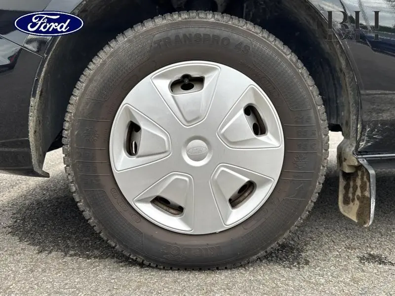 Gros plan sur la roue avant gauche du Ford Transit Custom noir Agate métallisé avec enjoliveur gris et pneu Transpro 45.