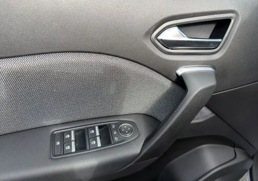 Gros plan sur la porte côté conducteur de la Renault Symbioz gris clair, montrant la poignée et les commandes des vitres électriques.
