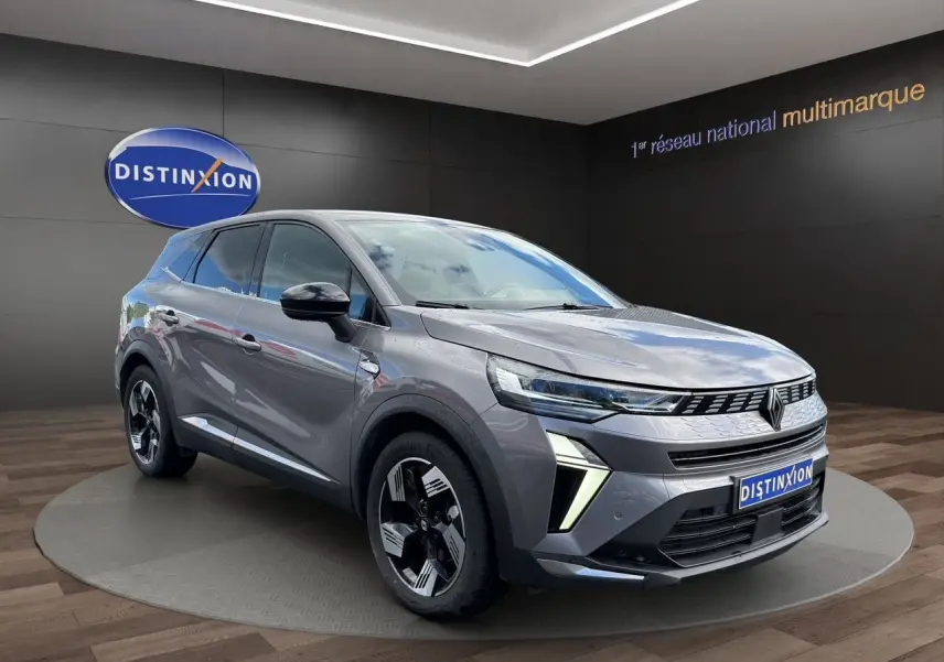 Vue 3/4 avant droit du Renault SYMBIOZ gris clair avec feux LED et jantes noires bicolores sur podium intérieur.