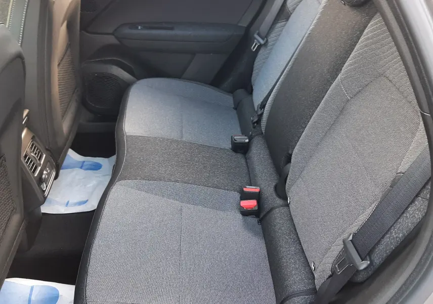 Vue intérieure côté droit des sièges arrière en tissu gris du Renault Captur 2025, version hybride, avec ceinture de sécurité visible.