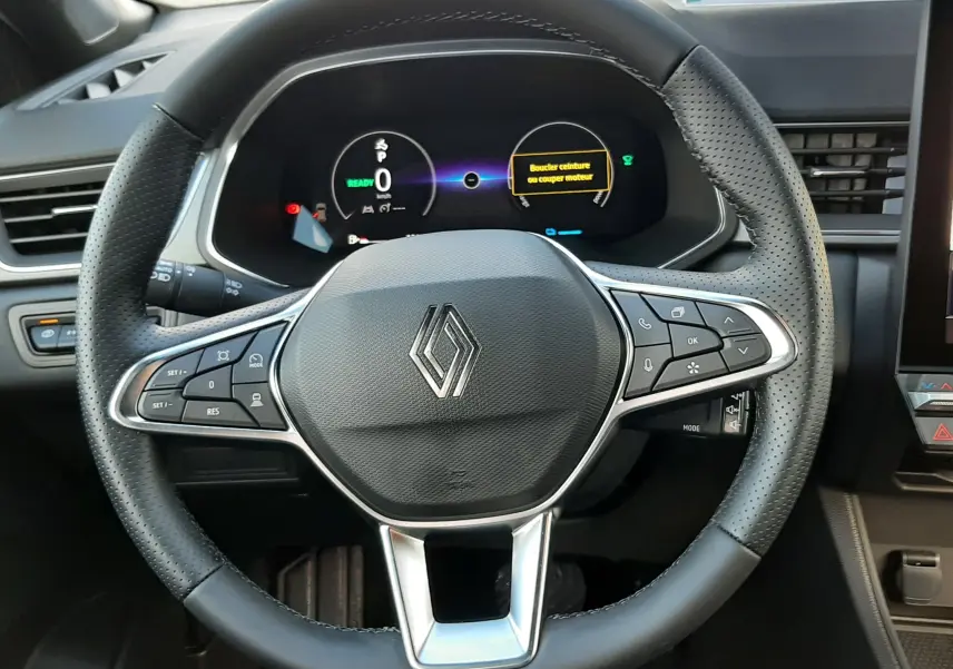 Vue rapprochée du volant noir perforé du Renault Captur 2025 avec tableau de bord numérique et commandes intégrées.