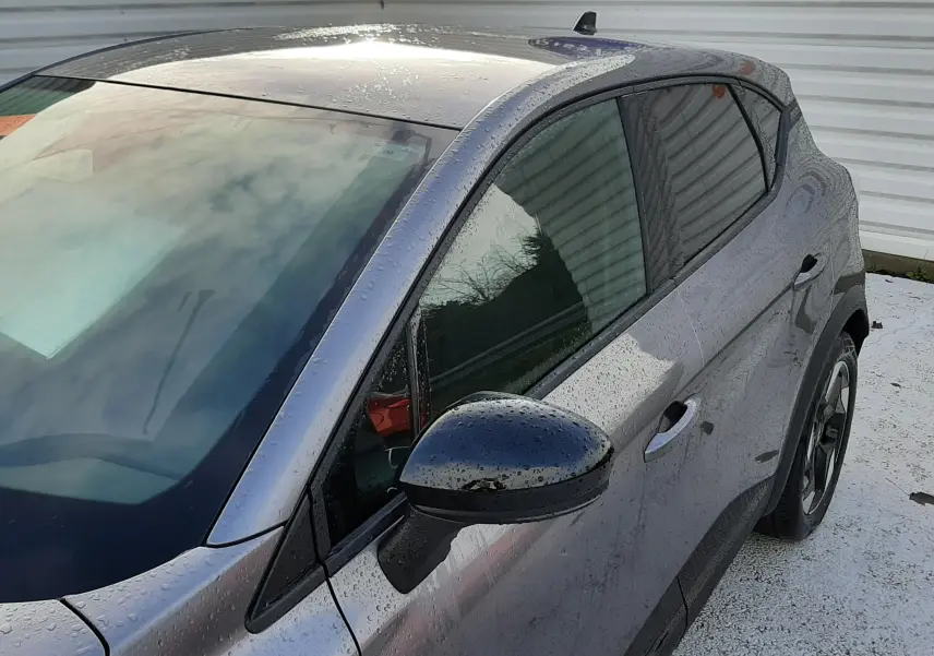 Vue 3/4 avant droit du Renault Captur gris Cassiopée avec rétroviseur noir et jantes alliage bicolores.