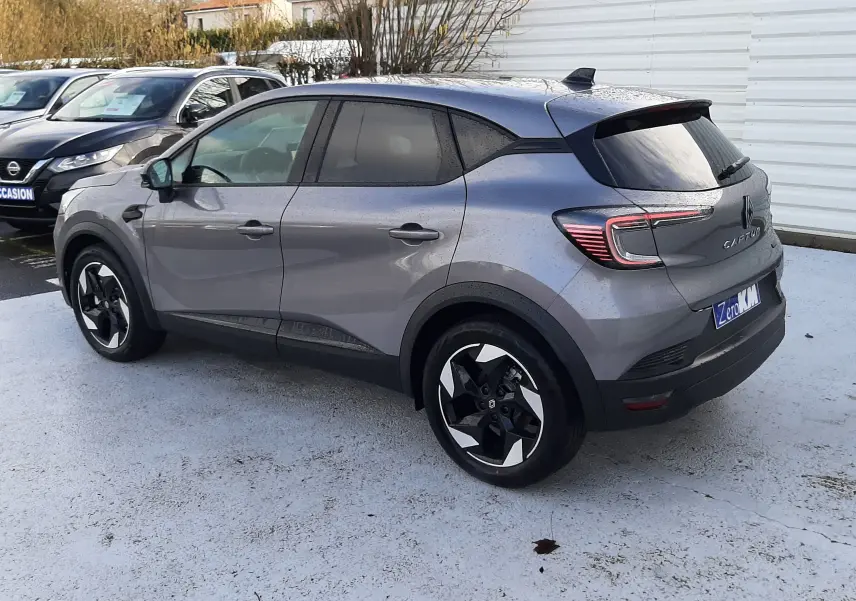 Renault Captur gris Cassiopée en 3/4 arrière droit, avec jantes bicolores et vitres teintées.