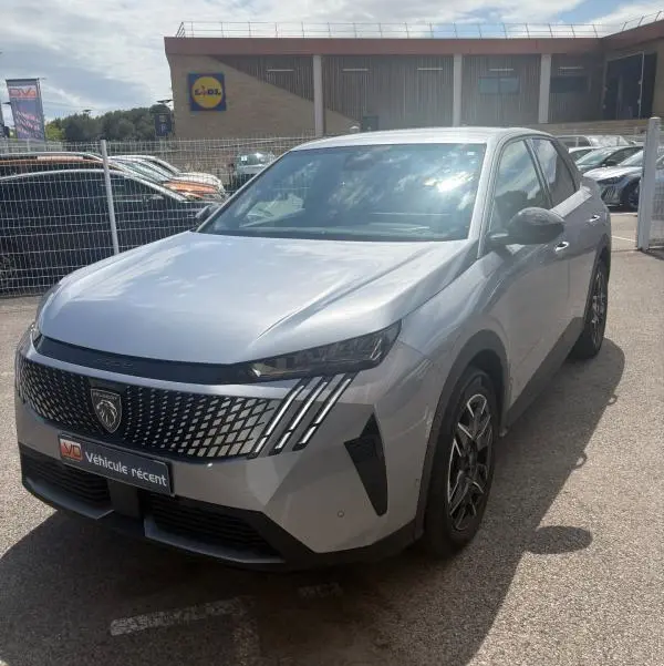 Peugeot 3008 Hybrid gris clair vue 3/4 avant droit, avec calandre distinctive et feux LED verticaux.