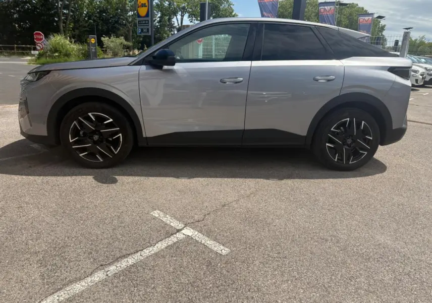 Vue de profil côté gauche d’un Peugeot 3008 Hybrid gris clair 2025 avec jantes noires et toit noir contrasté.