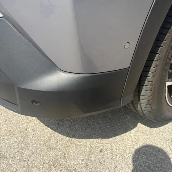 Détail de l'angle arrière droit du Peugeot 3008 Hybrid 136 e-DCS6 Allure gris clair avec pare-chocs noir et capteur de stationnement.