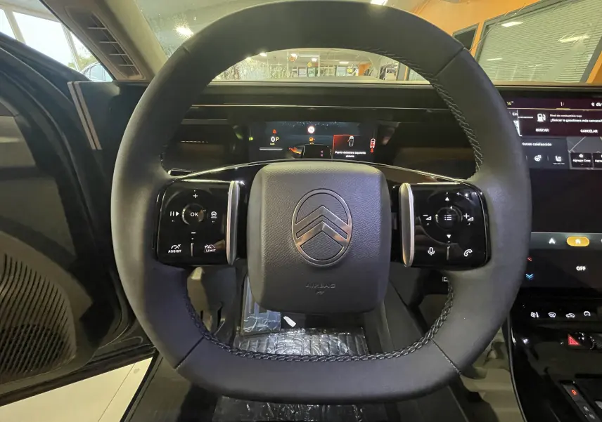 Vue rapprochée du volant noir du Citroën C5 Aircross hybride 2026 avec commandes tactiles intégrées.