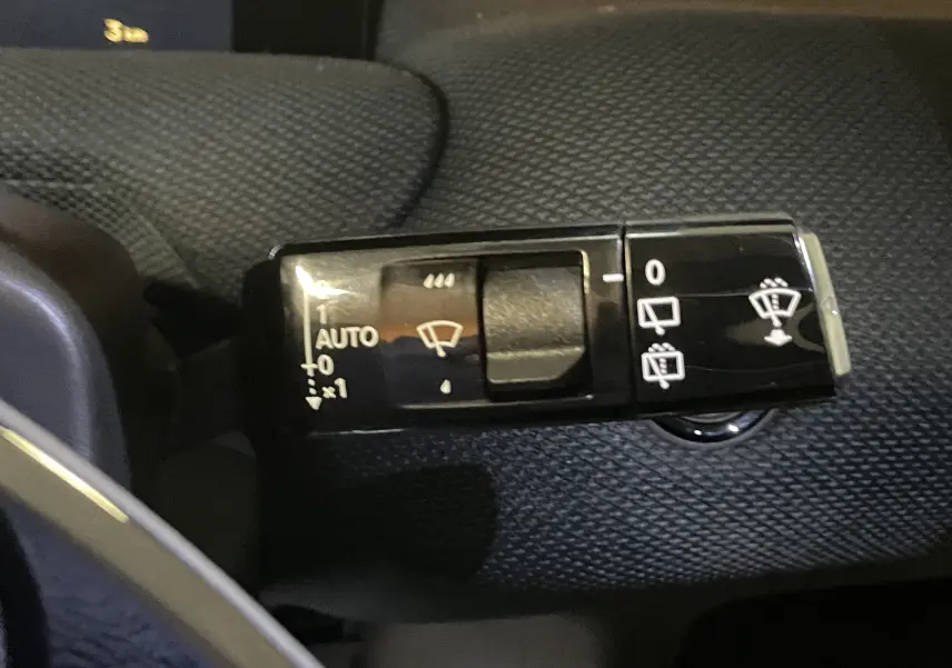 Gros plan sur la commande des essuie-glaces du Citroën C5 Aircross hybride 2026, bouton noir avec pictogrammes blancs.