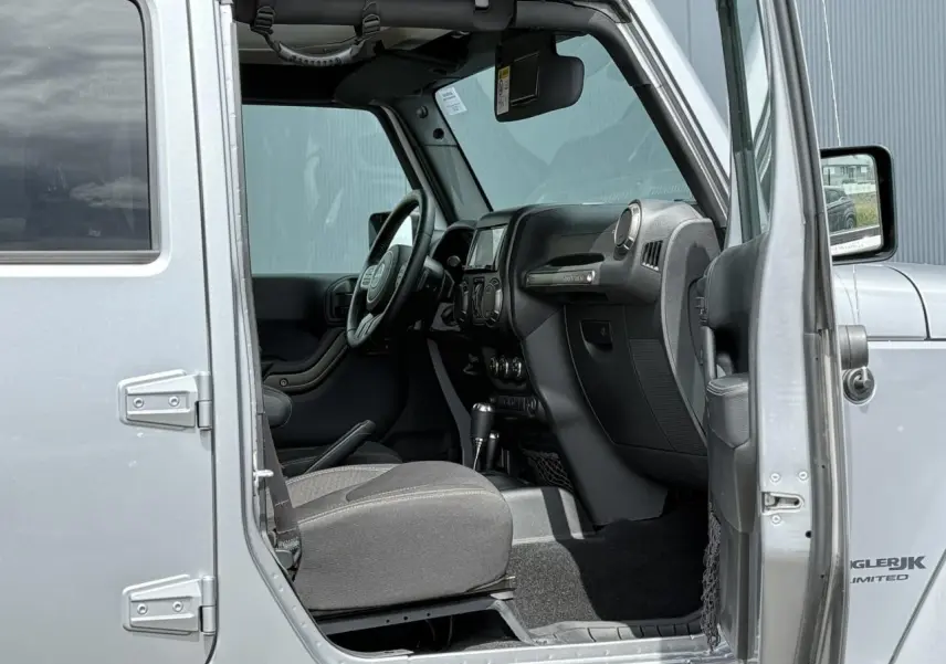 Vue intérieure côté conducteur d'une Jeep Wrangler Billet Silver 2019, mettant en valeur le tableau de bord et le volant multifonction.