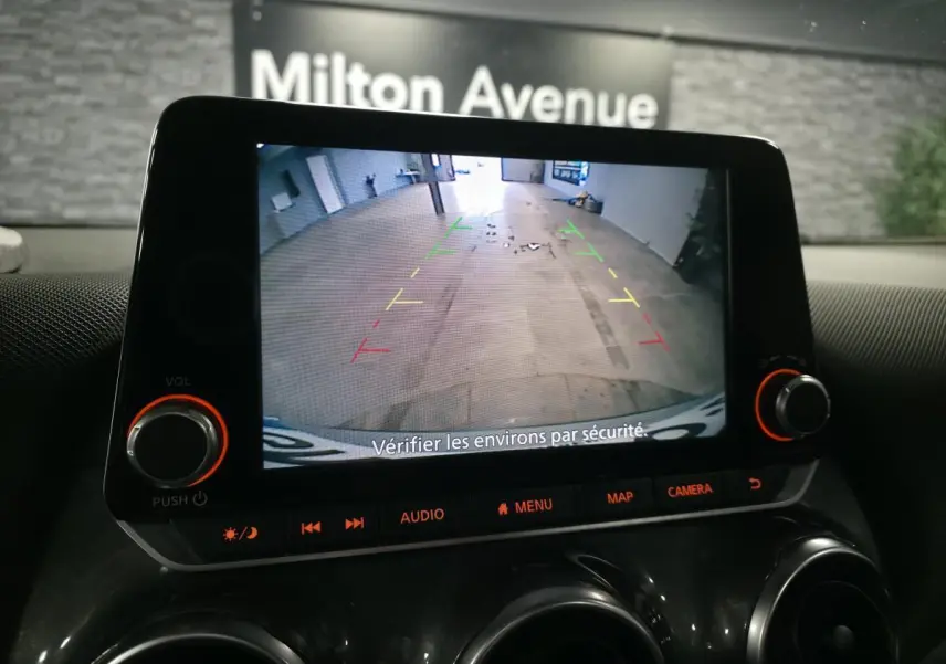 Écran tactile du Nissan Juke 2023 montrant la caméra de recul avec guidage coloré dans un garage.