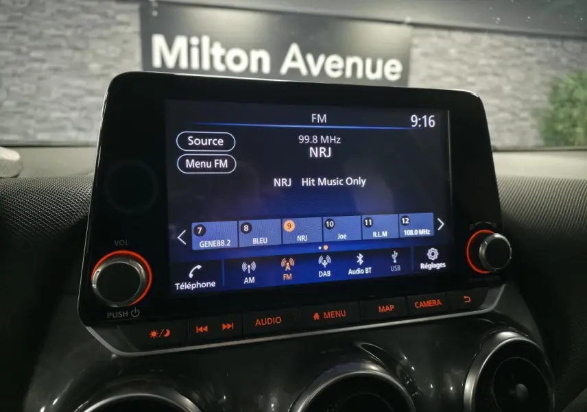 Écran tactile central du Nissan Juke 2023 affichant la radio FM NRJ, avec commandes audio et climatisation visibles.