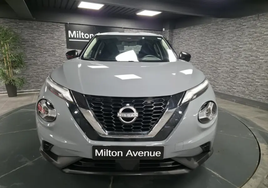 Vue frontale d'un Nissan Juke gris 2023 avec calandre noire en nid d'abeille et phares ronds distinctifs.