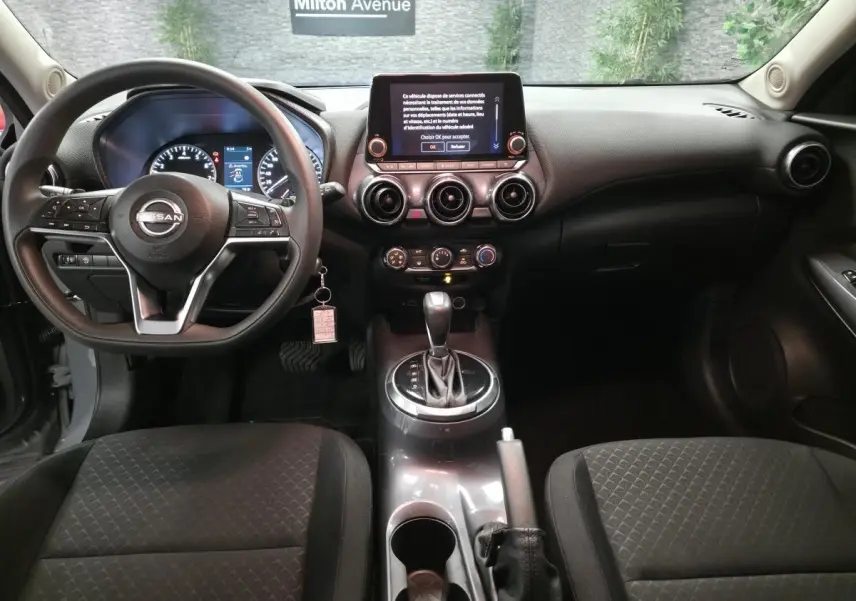 Intérieur noir du Nissan Juke 2023 vu de face, avec tableau de bord moderne et écran tactile central.