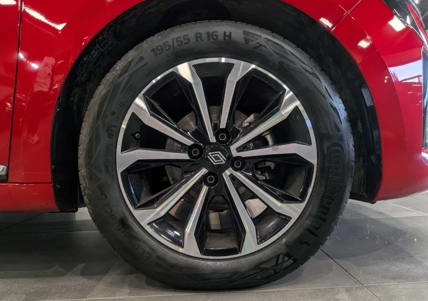 Gros plan sur la roue avant droite d'une Renault Clio V Rouge Flamme avec jante alliage bicolore.