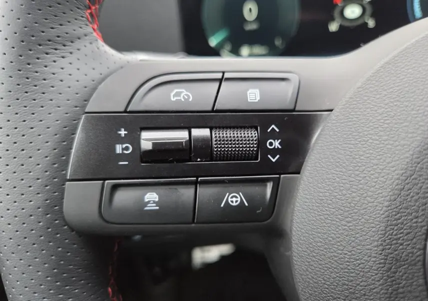 Gros plan sur les commandes noires à gauche du volant cuir perforé avec surpiqûres rouges du Hyundai Tucson N Line 2025.